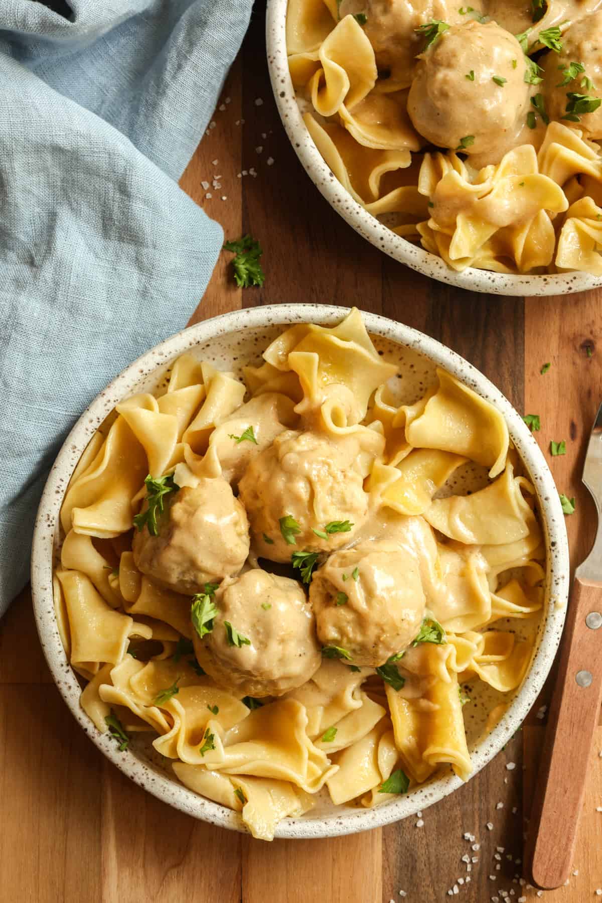 Swedish meatballs made with ground chicken served over egg noodles in a small dish, garnished with fresh parsley.