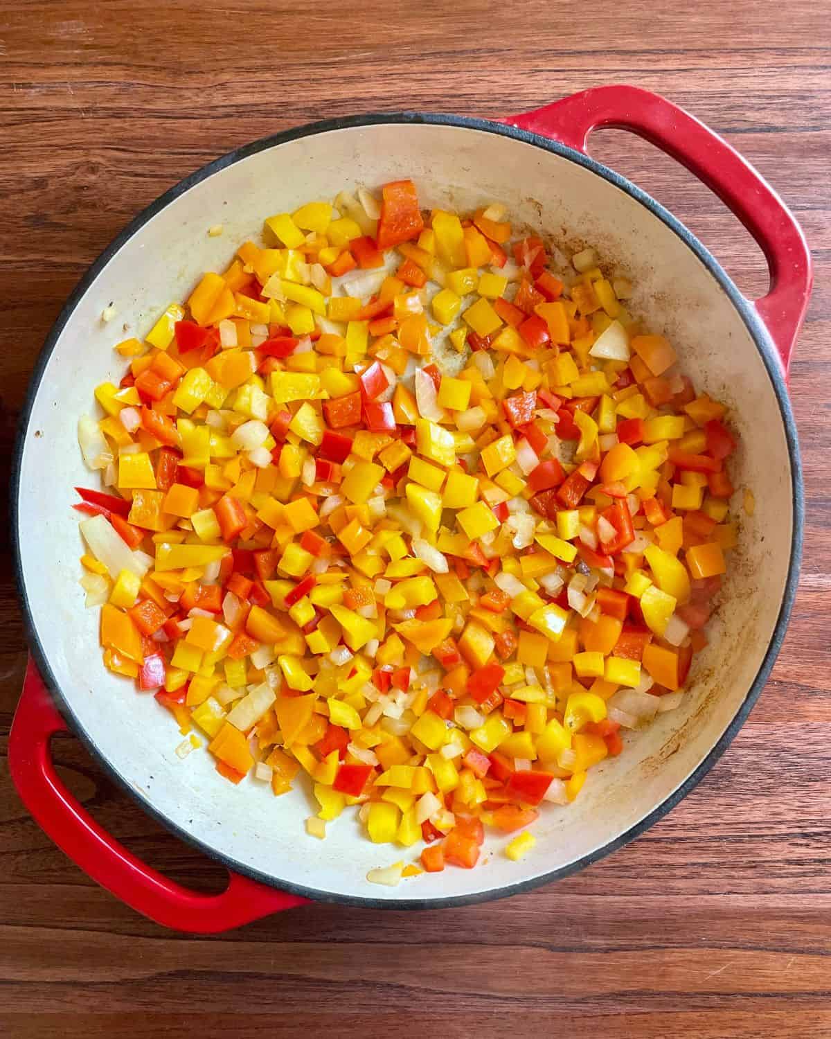 Bell peppers and onions cooking in a skillet.