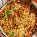 Stuffed peppers skillet in a red dish with a wooden spoon.
