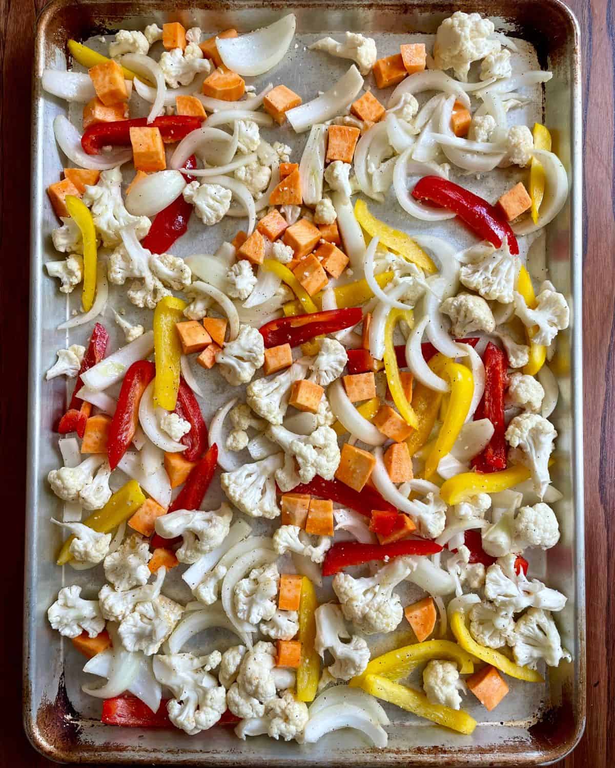 Chopped vegetables spread out on a sheet pan.