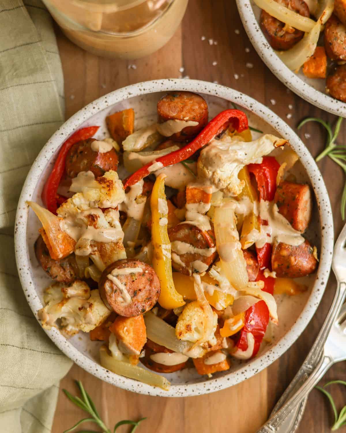 Veggies and chicken sausage in a bowl, drizzled with creamy balsamic dressing.