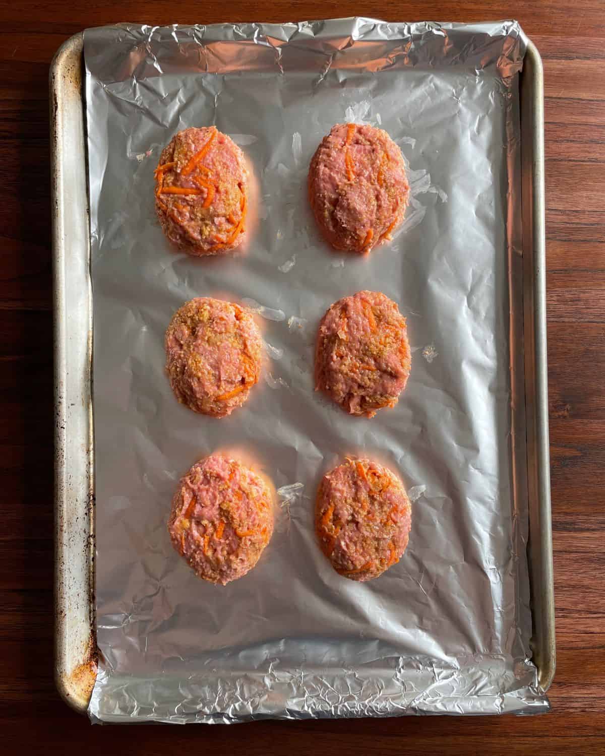 Mini meatloaves (made with ground turkey) on a foil-lined baking sheet, ready to go in the oven.