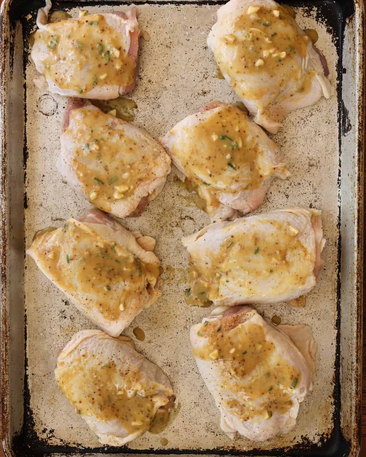 Raw chicken thighs brushed with glaze.