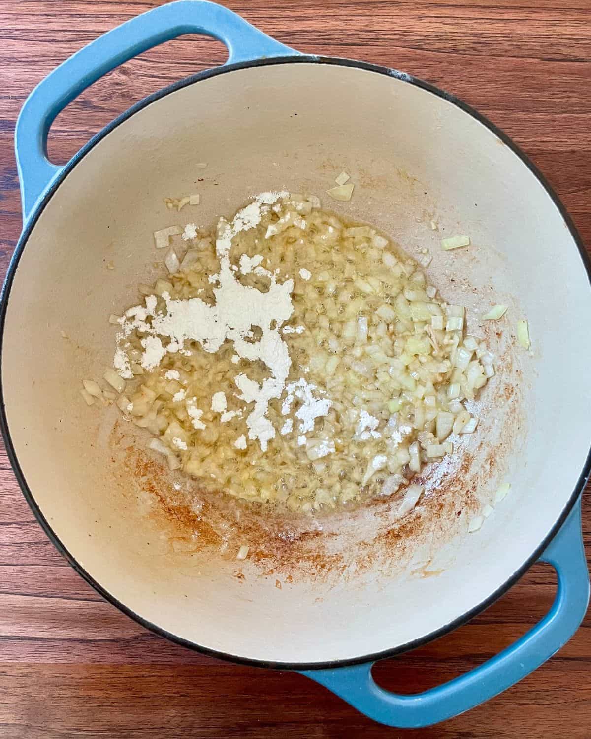 A Dutch oven with butter, flour, onions, and garlic.