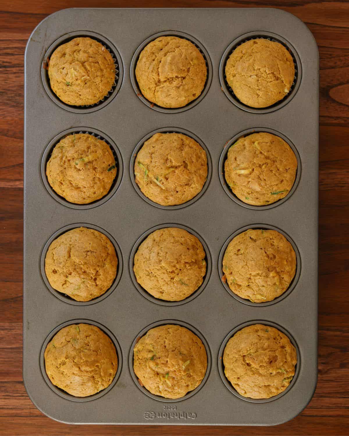Baked zucchini pumpkin muffins in a muffin tin.
