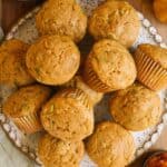 A plate piled high with freshly-baked pumpkin zucchini muffins.