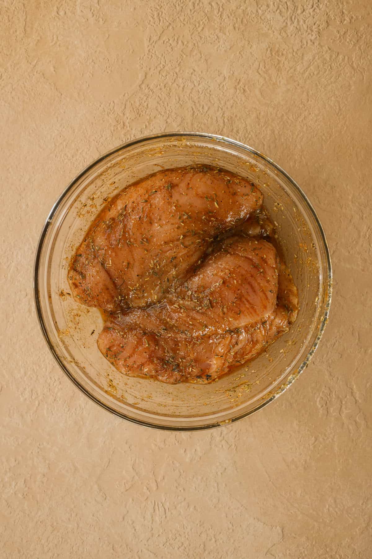 Raw turkey tenderloins in a bowl, covered in a seasoning rub.