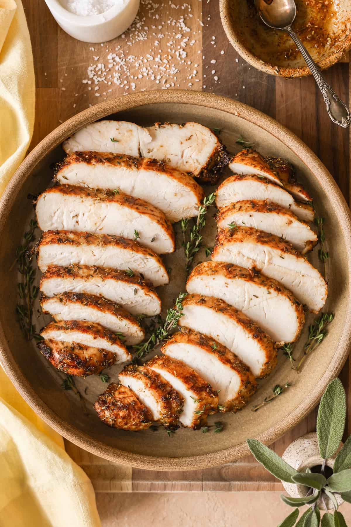Turkey tenderloins cooked in the air fryer, sliced and on a serving plate, garnished with fresh thyme.