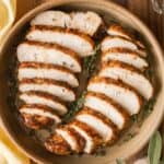 Sliced air fryer turkey tenderloin in a serving dish, garnished with fresh thyme.