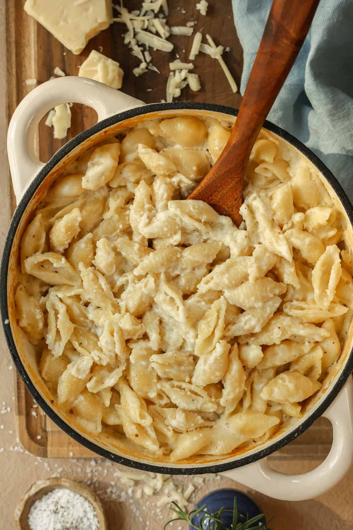 Homemade Dutch oven mac and cheese on a serving board with a wooden spoon.