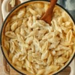 Homemade creamy mac and cheese in a small Dutch oven with a wooden spoon.