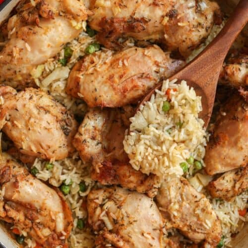 Up close image of the baked chicken and rice dish with a scoop of rice scooped up above the dish.