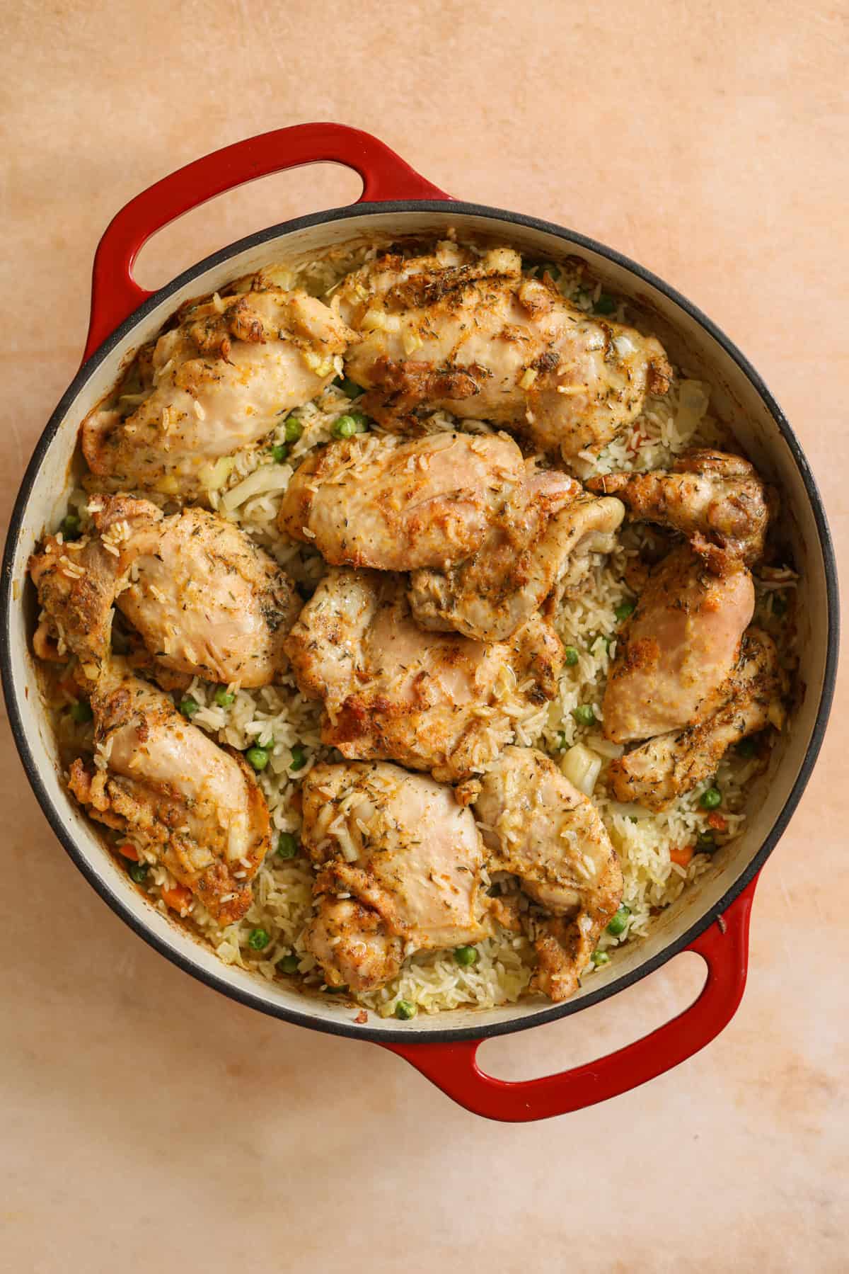 Oven-baked chicken and rice in a red skillet, fresh from the oven.