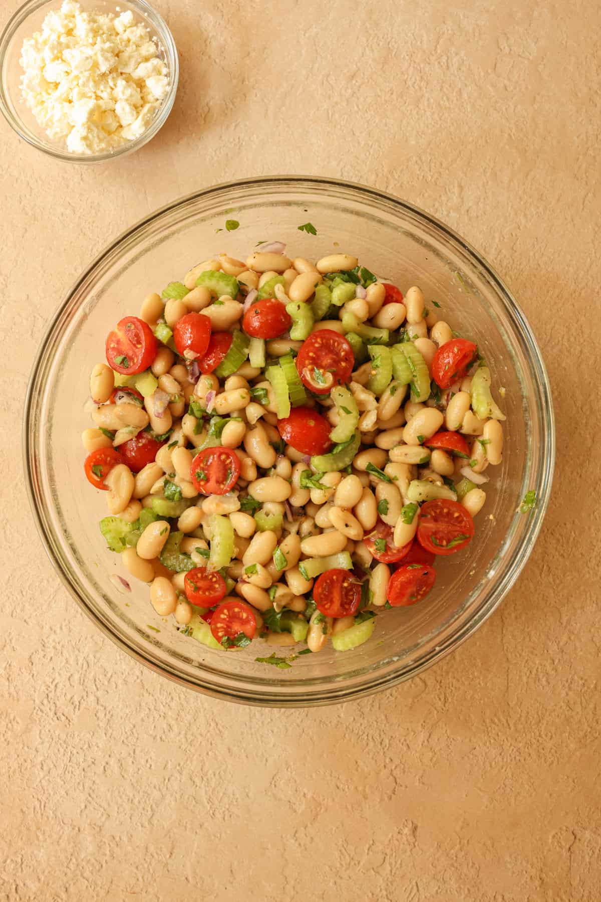 The white beans, celery, tomatoes, and onions have been mixed with the Greek lemon dressing. The feta is on the side and ready to be tossed into the salad.