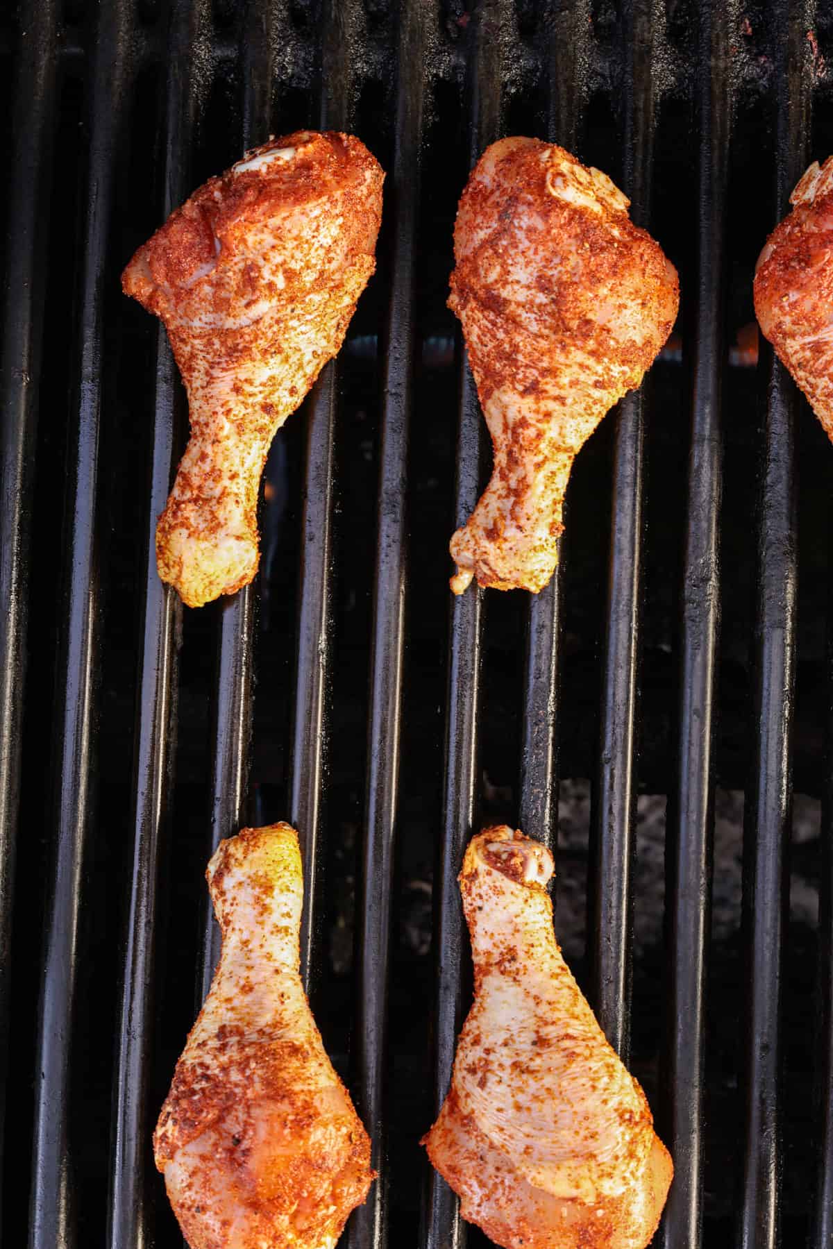 Chicken drumsticks covered in a BBQ dry rub, on the grill.