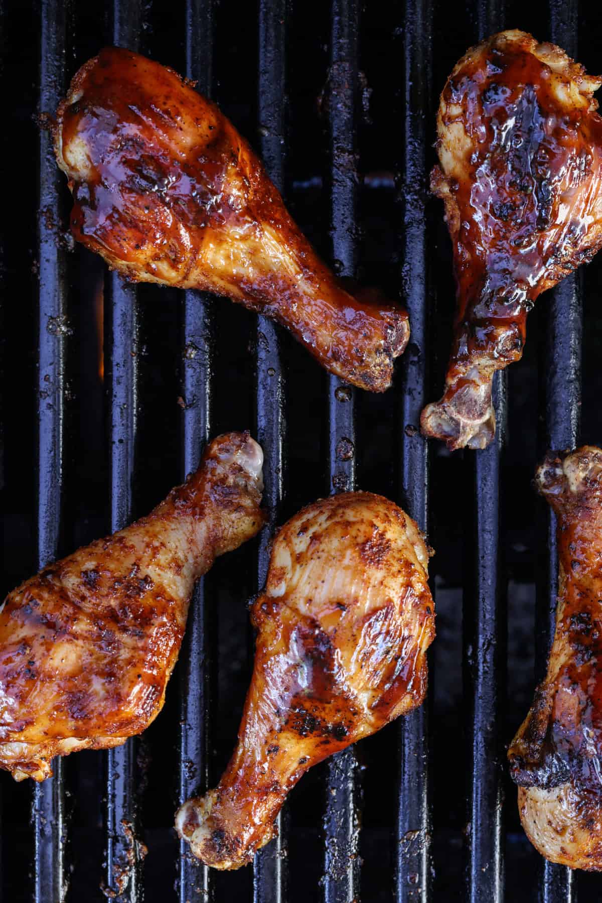 BBQ-smothered chicken drumsticks on the grill.