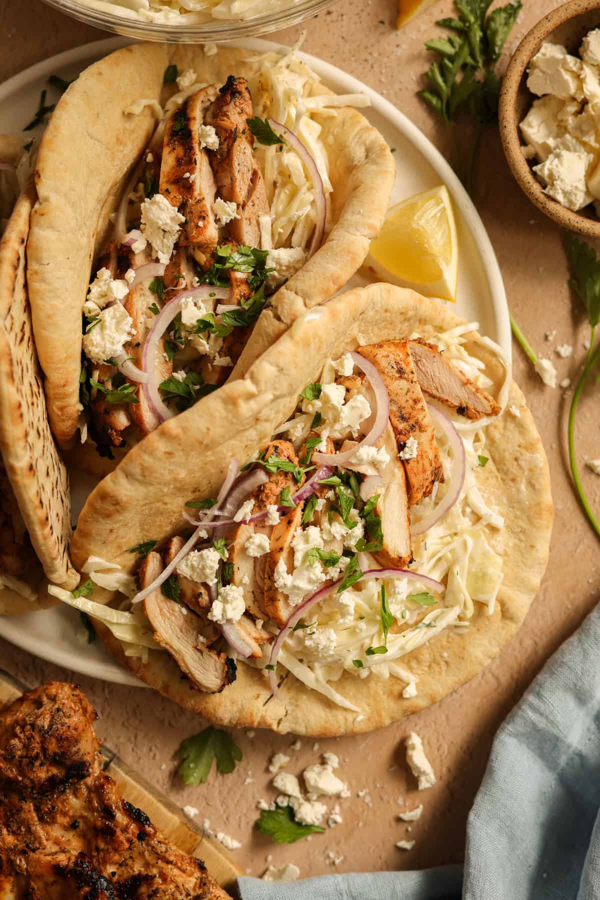 A platter of grilled chicken pitas stuffed with Tzatziki slaw, red onions, and feta cheese.