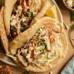 A plate of grilled chicken pitas stuffed with Tzatziki slaw, red onions, and feta cheese.