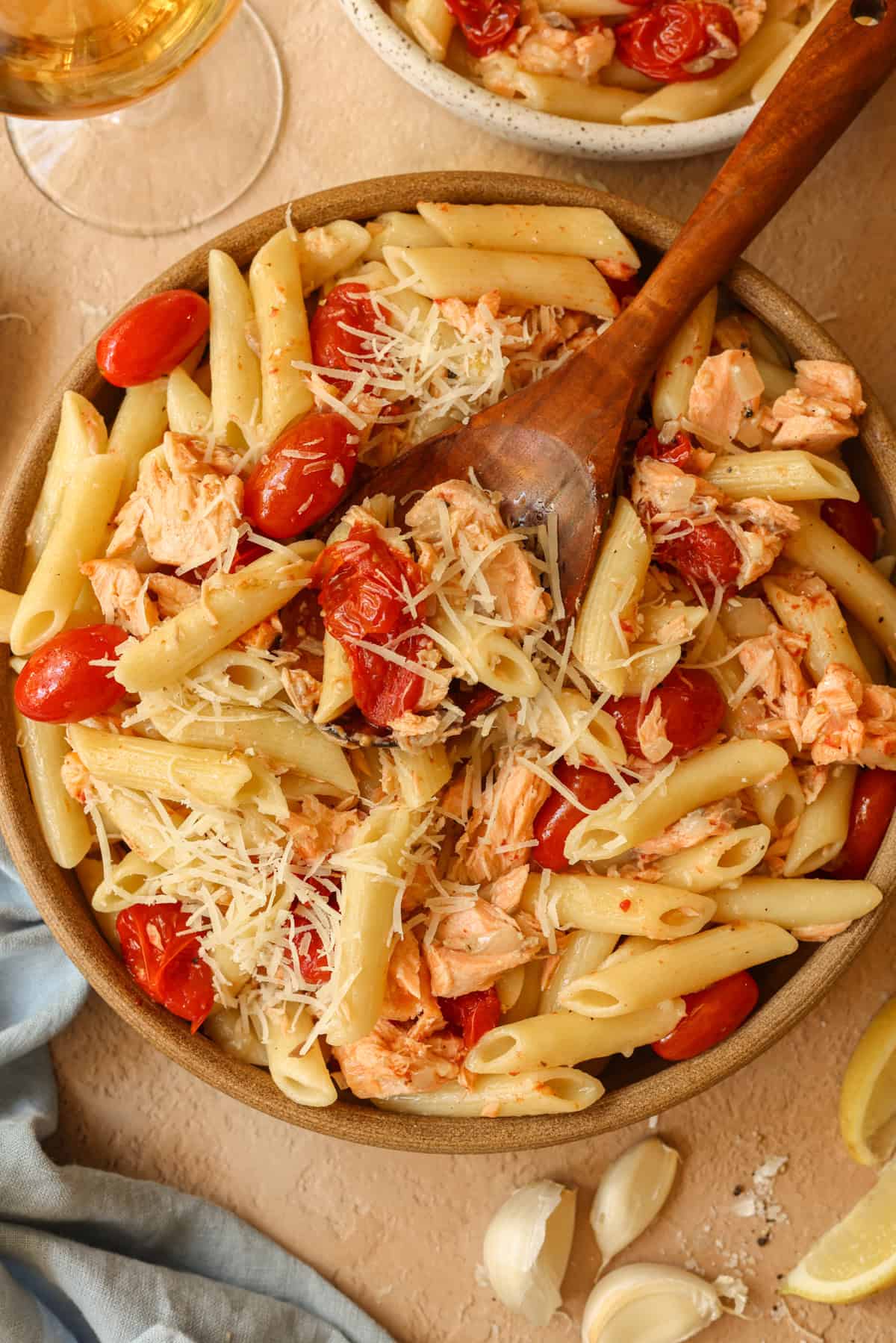 A large serving bowl containing salmon pasta (no cream) with roasted cherry tomatoes and a lemon garlic butter sauce.