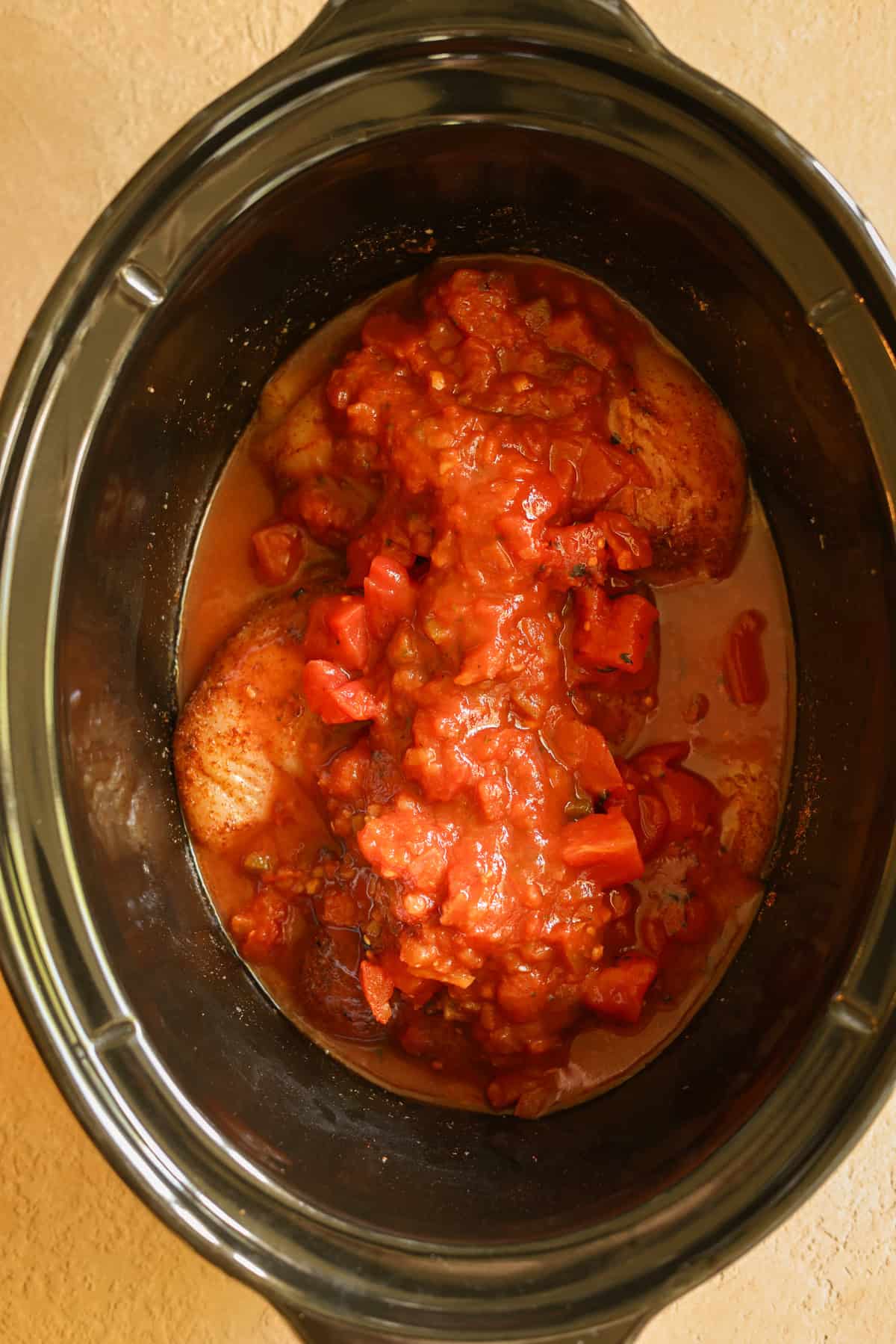 All of the ingredients needed for crock pot Mexican chicken, in the slow cooker, ready to cook.