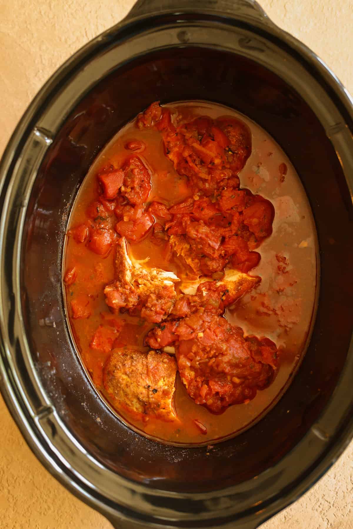 The slow cooker shredded chicken after it's finished cooking, ready to shred.