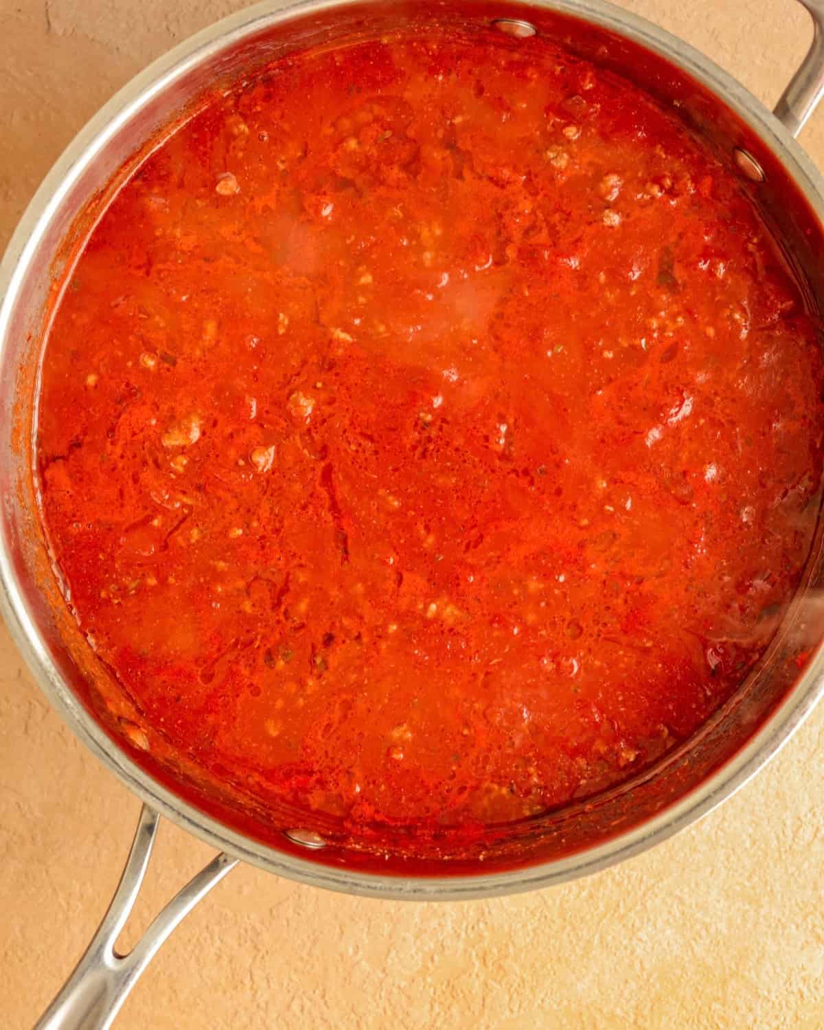 Pasta sauce combined with the cooked ground beef in a skillet.