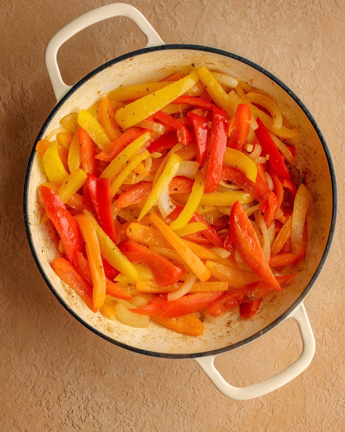Cooked peppers and onions in a skillet.
