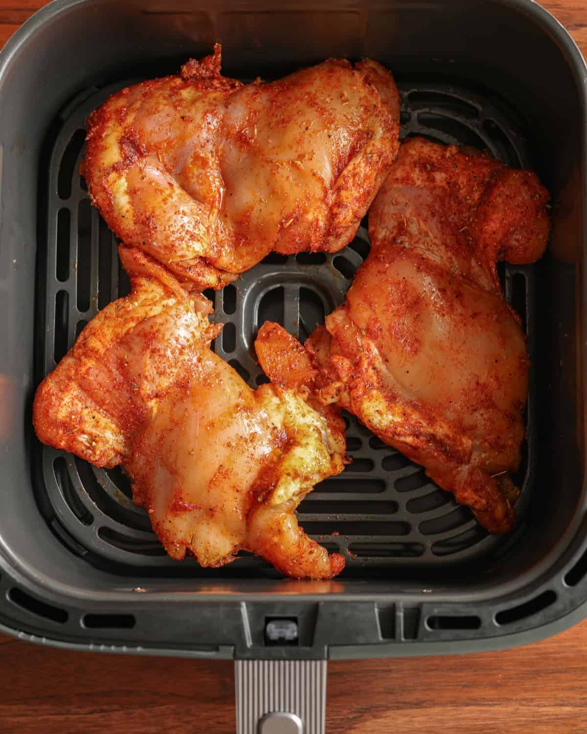Raw chicken thighs in an air fryer.
