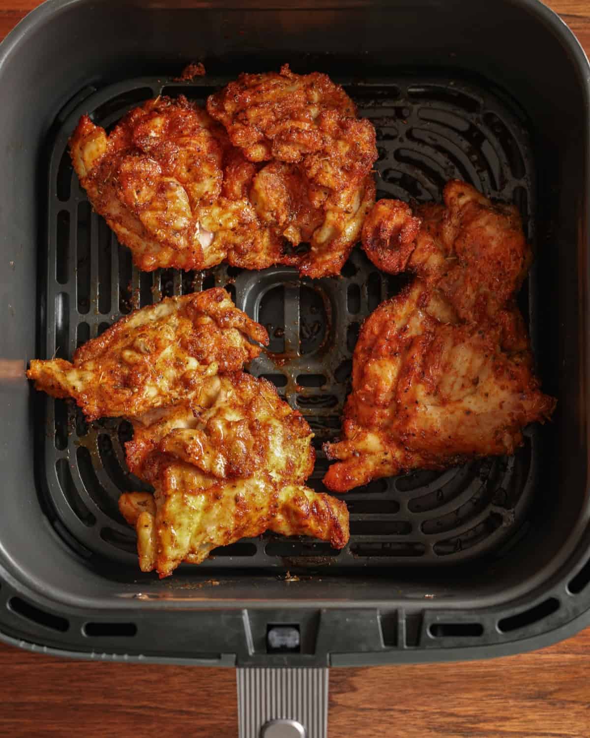 Partially cooked chicken thighs in an air fryer.