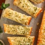 Garlic bread slices on parchment paper, garnished with fresh parsley.